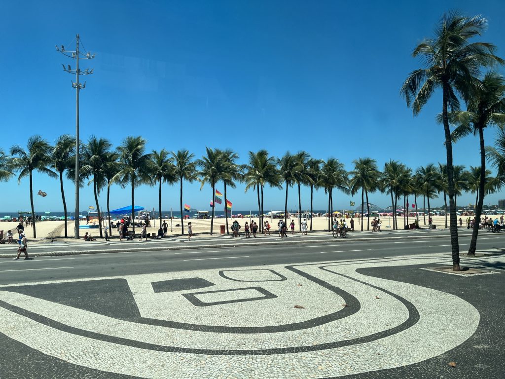 Row of palm trees along the Copacabana Beach promenade with the coastline curving into the distance in Rio de Janeiro