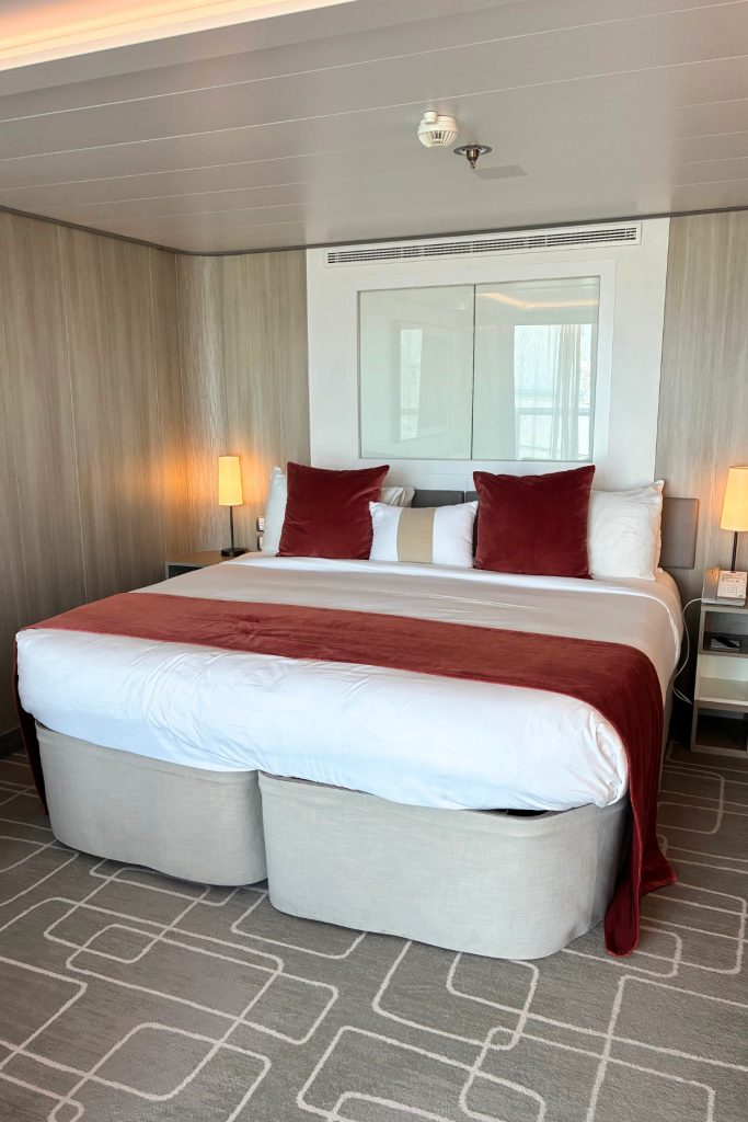 Sky Suite bedroom on Celebrity Beyond with king bed and red and white bedding