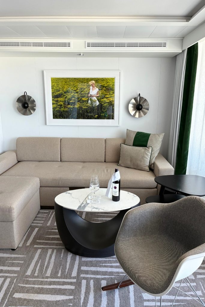 Celebrity Suite living area on Celebrity Beyond with sofa, wine service, and artwork above seating