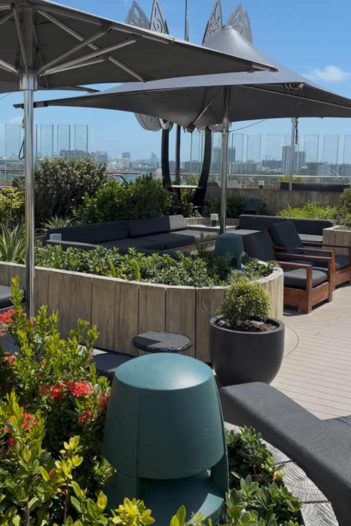 Rooftop Garden on Celebrity Beyond with lounge seating, umbrellas, and city skyline view