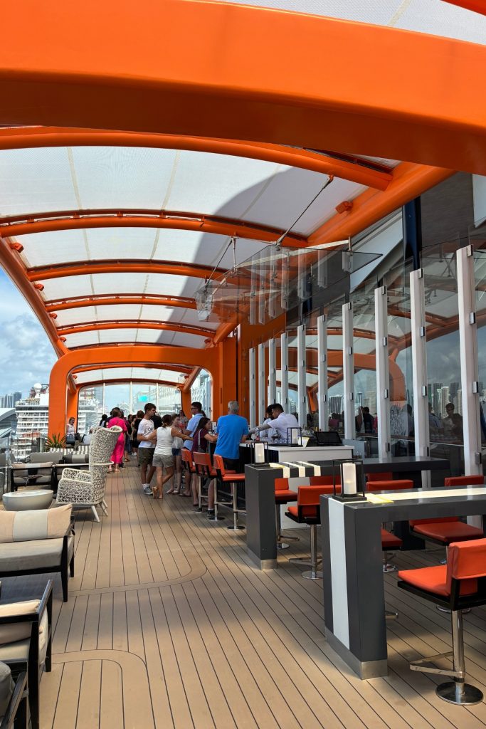 Magic Carpet platform on Celebrity Beyond with orange canopy, bar seating, and skyline view