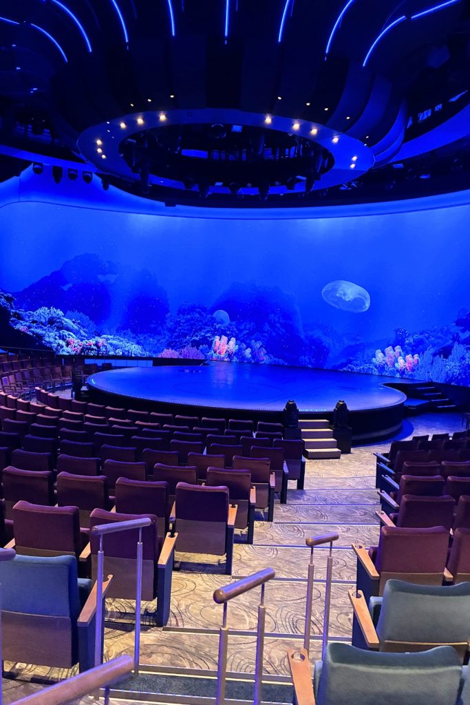 Main Theatre on Celebrity Beyond with tiered seating and blue-lit stage backdrop