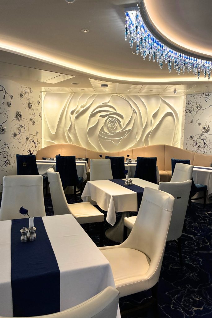 Blu restaurant on Celebrity Beyond with white and navy table settings and sculpted wall art