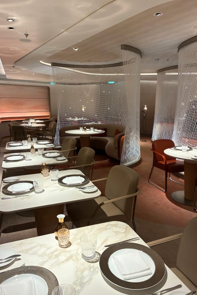 Le Voyage restaurant on Celebrity Beyond with draped fabric ceiling and elegant table settings