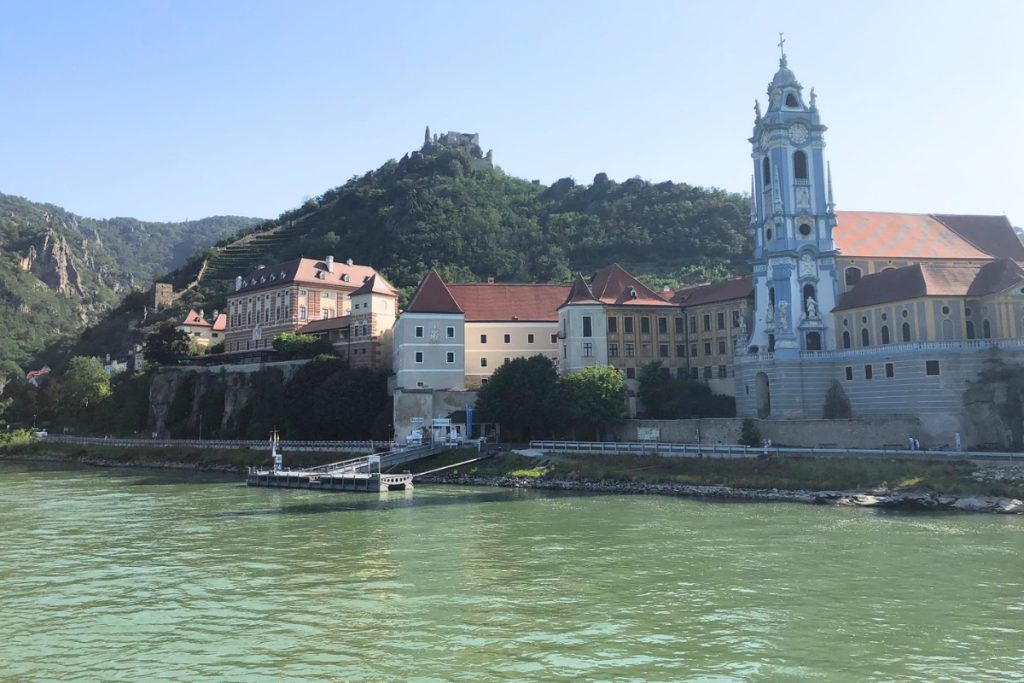 Dürnstein Abbey's blue and white baroque church tower and the ruined hilltop castle above, seen from the Danube River.