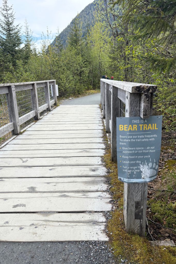 A wooden boardwalk trail sign warning hikers that the path to Nugget Falls is an active bear trail.