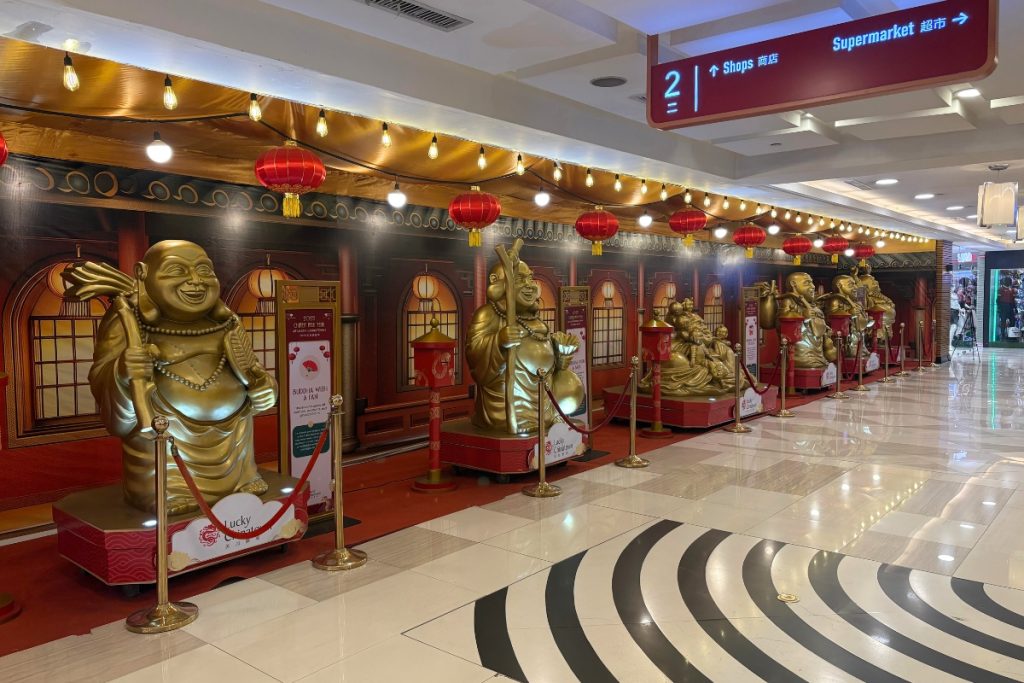 Row of gold Buddha statues on individual pedestals lining a hallway at Lucky Chinatown Mall in Manila