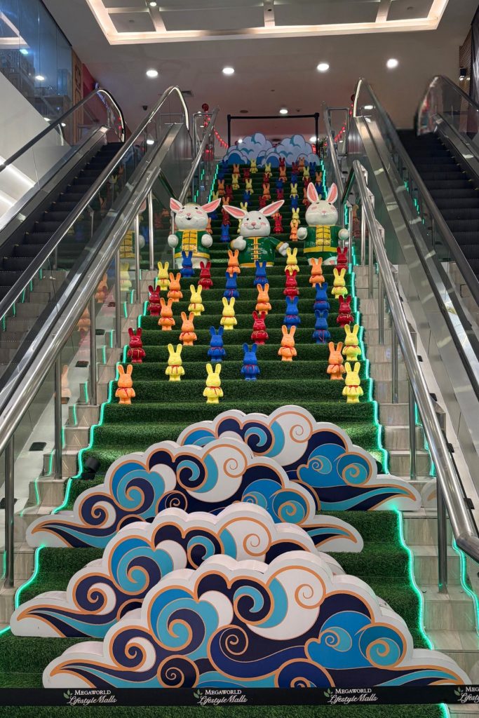 Staircase decorated with AstroTurf, wave graphics, and rows of painted rabbit figurines at Lucky Chinatown Mall in Manila