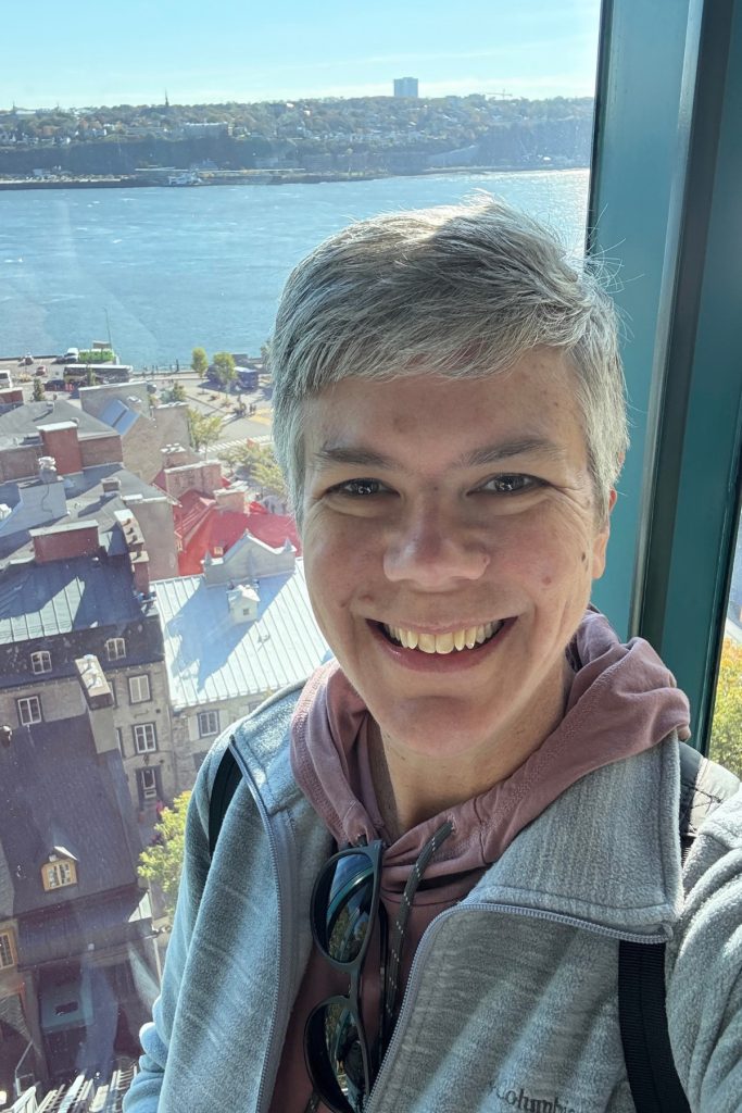 Selfie inside the Quebec City funicular car, with Lower Town rooftops and the St. Lawrence River visible through the window.