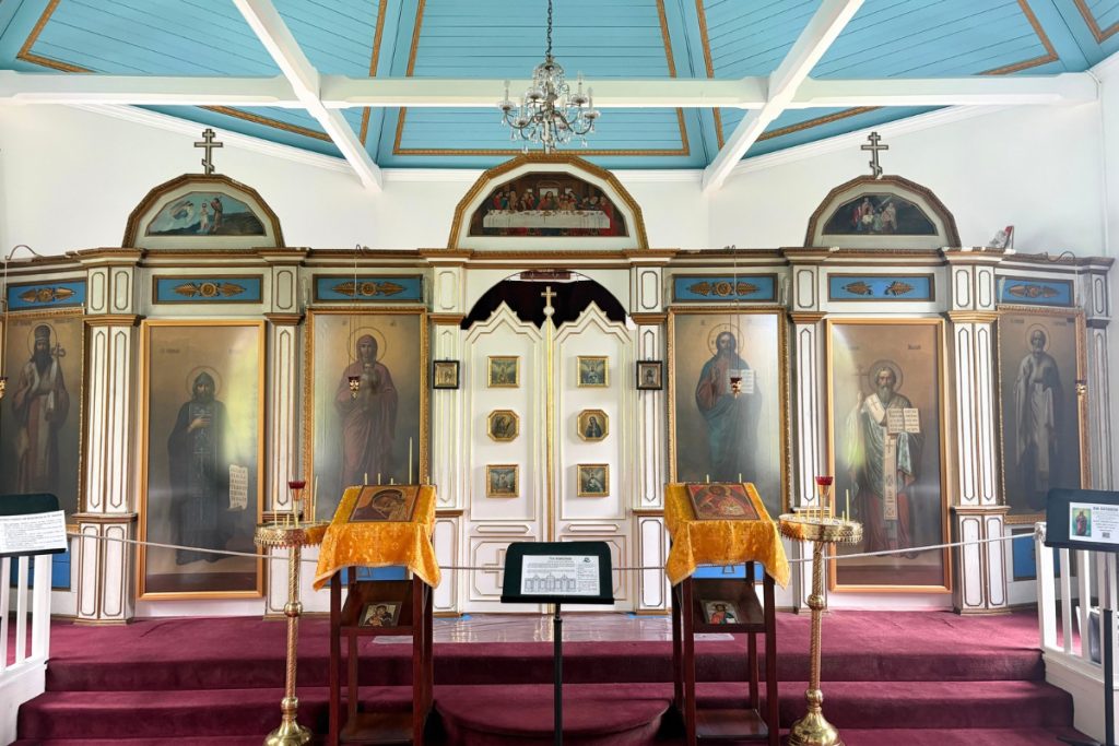 The blue and gold painted interior of Saint Nicholas Russian Orthodox Church in Juneau, showing the iconostasis and altar.