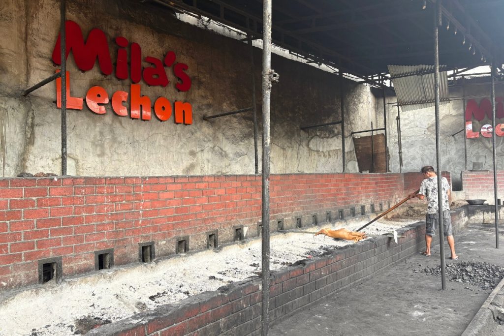 A whole pig roasting over hot coals at Mila's Lechon in La Loma, Manila