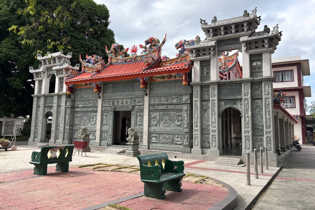 Chong Hock Tong temple facade with carved stone gate and ceramic dragon roof ornaments at Manila Chinese Cemetery