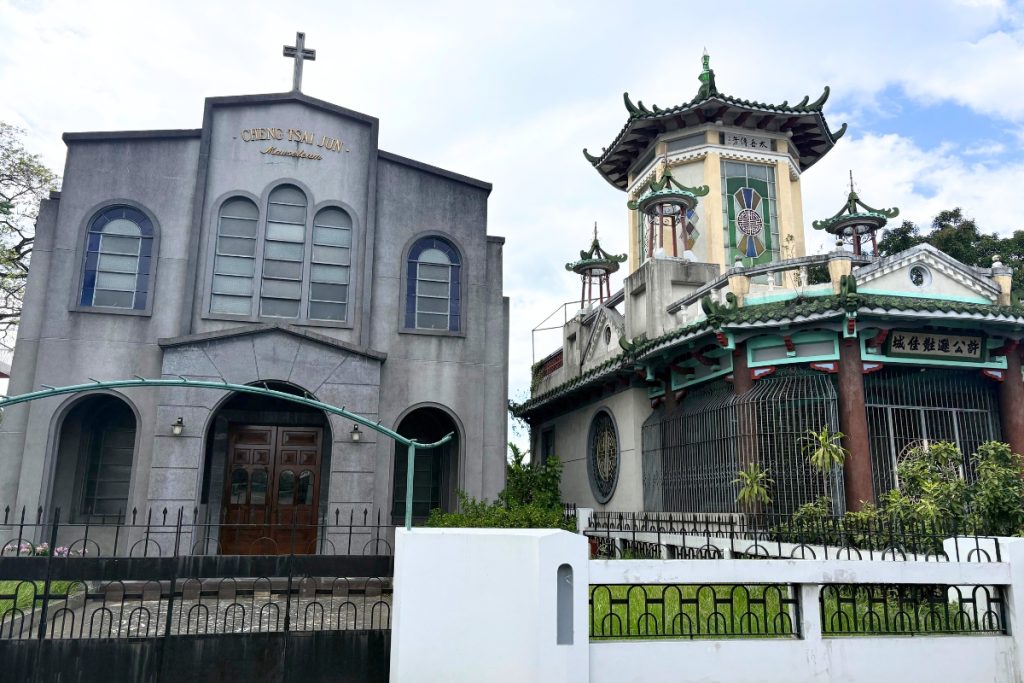 Chapel-style family mausoleum with a cross, beside a green-roofed pagoda-style tomb at Manila Chinese Cemetery