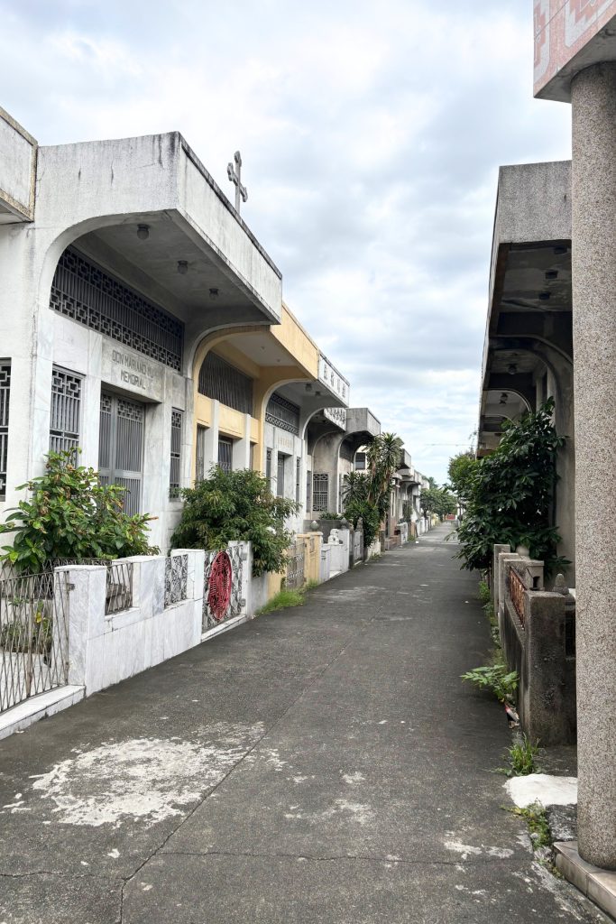 Row of family mausoleums resembling small houses along a quiet street at Manila Chinese Cemetery