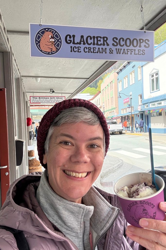 A woman holding a cup of ice cream outside Glacier Scoops in downtown Juneau in 2025.