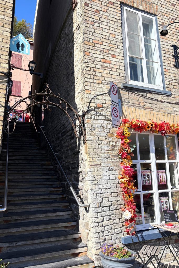A narrow stone staircase between buildings on a side street in Quebec City's Petit-Champlain district.