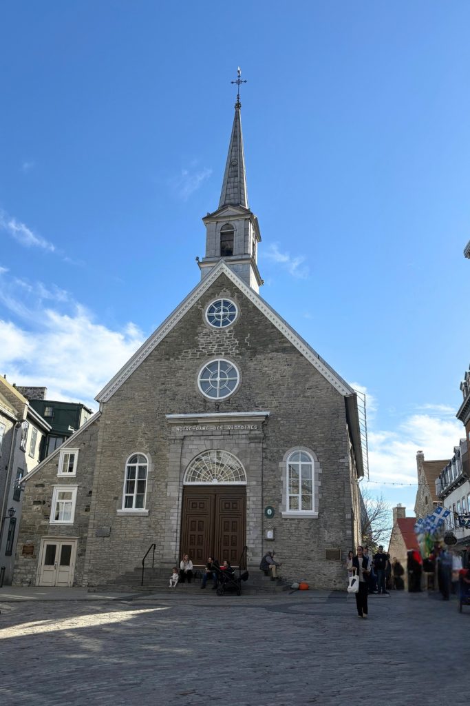 Notre-Dame-des-Victoires, a stone church with a steeple, on the cobblestone square of Place Royale in Quebec City.