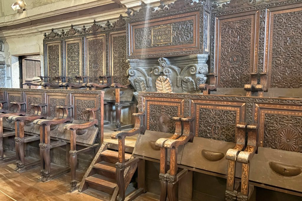 Carved dark wood choir stalls inlaid with gold at San Agustin Church, inscribed with "INCIPIT CHORUS"