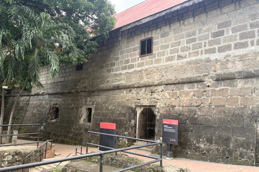Stone exterior of Baluarte de Santa Bárbara bastion at Fort Santiago, Manila, with a red-roofed structure above