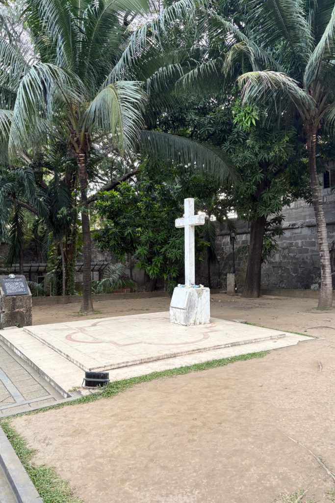 White marble cross marking a mass grave near the entrance to the dungeons at Baluarte de Santa Bárbara, Manila